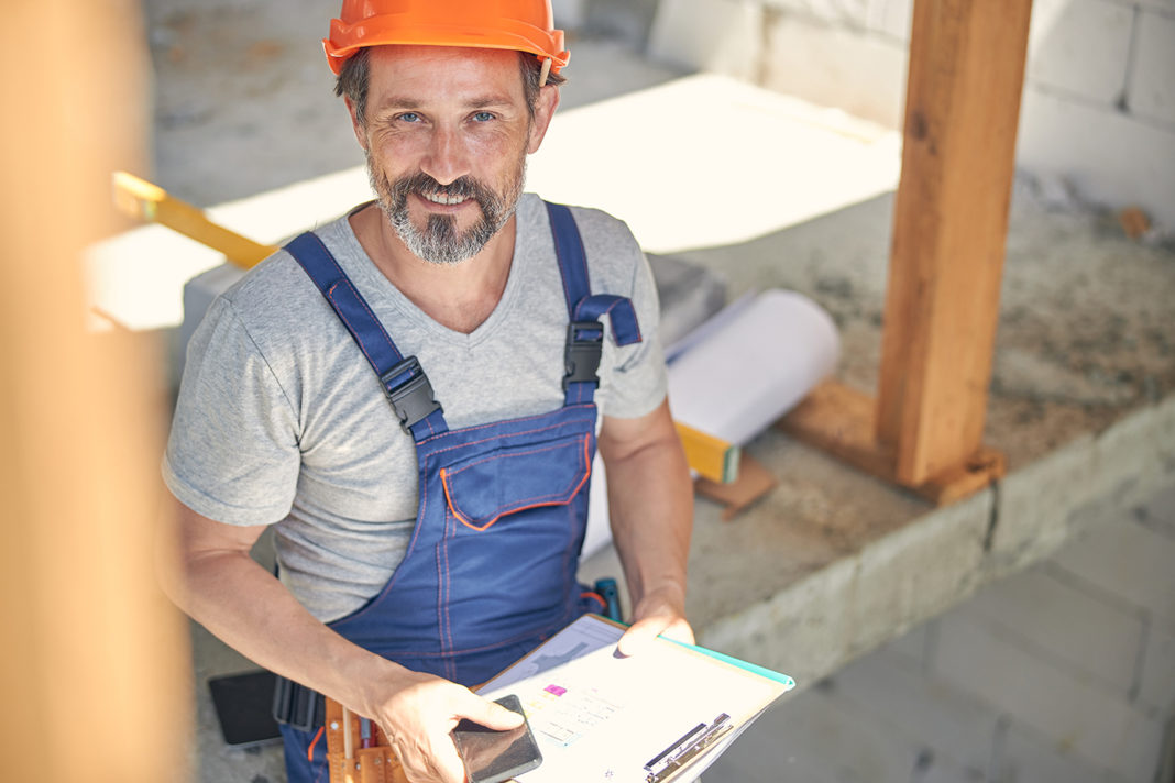 Man in overalls holding a mobile phone